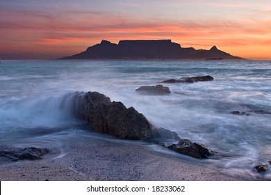 The colors of Table Mountain at sunset with large rock in foreground