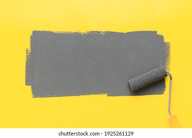 Colors of the year 2021 Ultimate Gray and Illuminating Yellow. Paint roller painting a gray stripe on a yellow background. Minimalistic composition with copy space