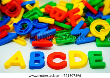 Colorul plastic letters spelling text ABCDE with pile of colorful letters background