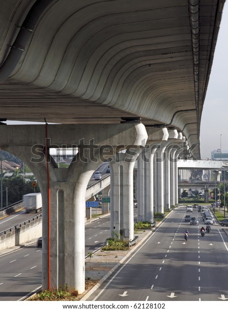 Colossal concrete column holding up a massive\
elevated highway.