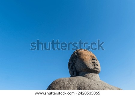 The colossal statue of Gommateshwara Bahubali stands tall against a clear blue sky at Shravanabelagola, representing a significant site of Jain pilgrimage.