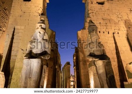 Colossal statues of Ramesses II (Ramses II) in Luxor temple illuminated at night, in Luxor, Egypt