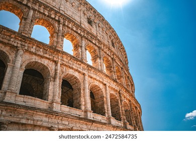 Colosseum in Rome, Italy. This beautiful, ancient landmark is a popular tourist destination. The sun shines through and reflects against its many arches.
