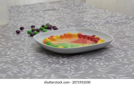 Coloured Sweets On A Shallow White Dish Have Diffused Their Colours In A Home Science Experiment.