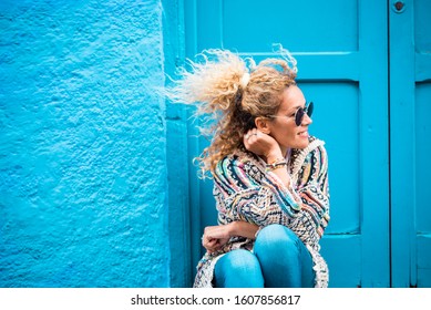 Coloured And Trendy Lifestyle Fashion Portrait Of Beautiful Young Caucasian Middle Age Woman Looking On Left Side - Blue Traditional Old Home Background And Door