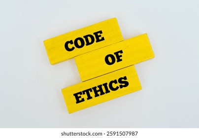 Coloured wooden block with text CODE OF ETHICS  on white background. Morality, principles and professional standards concept