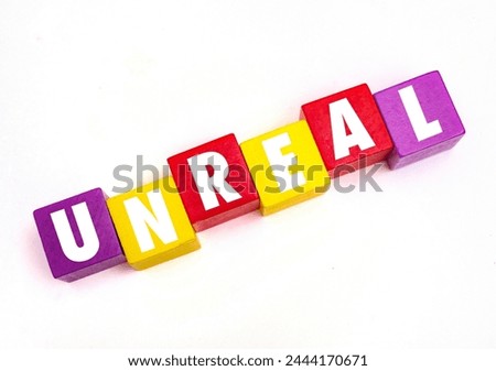 A coloured wooden block with word  “UNREAL” on it