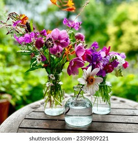 Colourful arrangement of English country garden flowers in three glass vases on outdoor table. Natural and nostalgic. Sweet peas, crocosima, anemones daisies alliums and dahlias. - Powered by Shutterstock