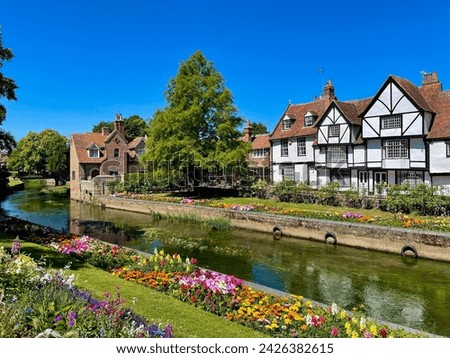 Colourful array of blooming flowers and charming old timbered houses by the slowly flowing River Stour. Idyllic scenery in picturesque medieval historic town of Canterbury on a beautiful summer day.
