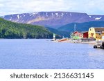 Colourful buildings along shore of Bonne Bay with the Tablelands on the horizon at Norris Point during Summer