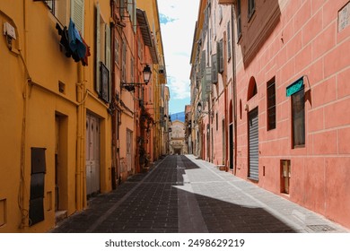 Colourful buildings line a narrow street leading to a distant church. Vibrant facades, iron lamp posts, and shuttered windows. Translation of phrase on church facade: "in me is all the hope of life" - Powered by Shutterstock