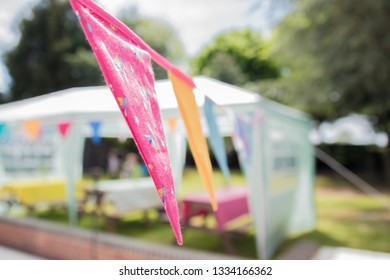 Colourful Buntings Hanging In The Garden With A Marquee In The Background - At A British Garden Party In Summer. 