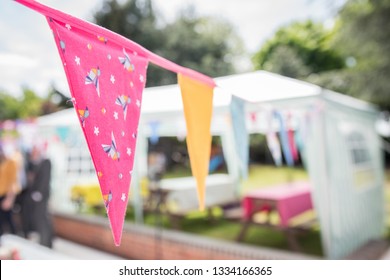 Colourful Buntings Hanging In The Garden With A Marquee In The Background - At A British Garden Party In Summer. 