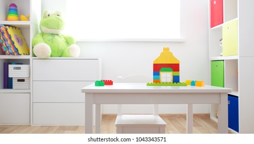 Colourful children rooom with white walls and furniture. Rainbow carpet at home interior with a window