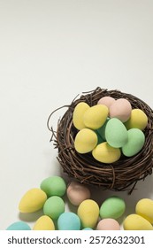 Colourful chocolate mini easter eggs in a bird’s nest isolated against white with copy space.