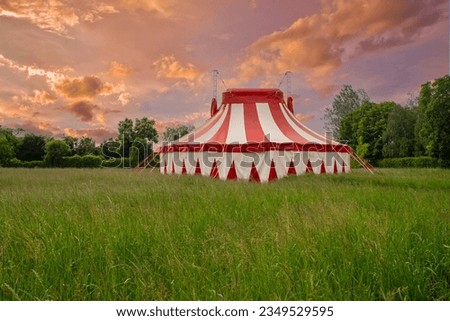 Colourful circus tent on green meadow against a colorful sunset sky