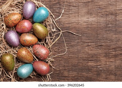 colourful easter eggs and straw on wooden table top