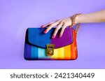 Colourful fashion rainbow purse with beautiful hand. isolated on purple background.