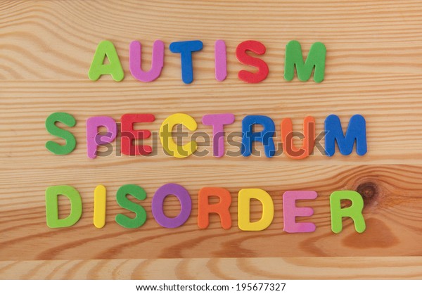Colourful foam letters spelling out Autism\
spectrum disorder on a wooden\
background