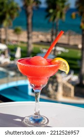 Colourful Frozen Pink Strawberry Daiquiri Cocktail Drink Served In Glass At Outdoor Cafe Overlooking Blue Pool, Sea And Palm Trees, Relax And Holidays At Sea