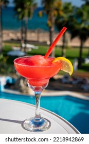 Colourful Frozen Pink Strawberry Daiquiri Cocktail Drink Served In Glass At Pool Bar Overlooking Blue Pool, Sea And Palm Trees, Relax And Holidays At Sea