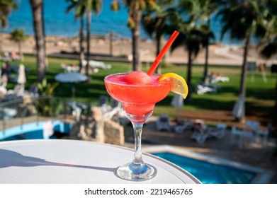 Colourful Frozen Pink Strawberry Daiquiri Cocktail Drink Served In Glass At Pool Bar Overlooking Blue Pool, Sea And Palm Trees, Relax And Holidays At Sea