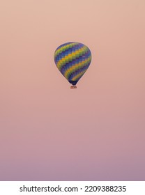 Colourful Hot Air Ballon Flying During A Pastel Pink Sunrise In Cappadocia, Turkey