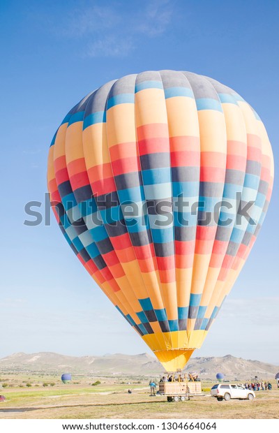 colourful hot air balloon landing on a\
truck in a field on a sunny day for transportation \
