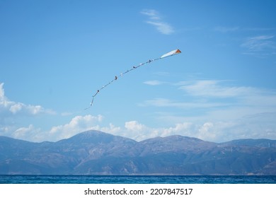  Colourful Kite Flying In Blue Sky With The Sea And Mountains In The Background                              