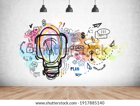 Colourful light bulb with ideas and business strategy, plans and messages drawn on a concrete wall in office room with parquet. Concept of idea and plan