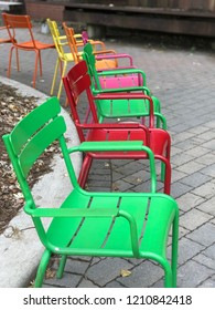 Colourful Metal Chairs Arranged In A Semi Circle. Yellow, Green, Orange, Pink.