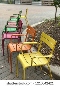 Colourful Metal Chairs Arranged In A Semi Circle. Yellow, Green, Orange, Pink.