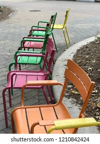 Colourful Metal Chairs Arranged In A Semi Circle. Yellow, Green, Orange, Pink.