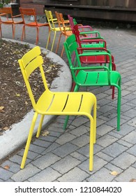 Colourful Metal Outdoor Chairs In A Semi Circle Arrangement On A Patio
