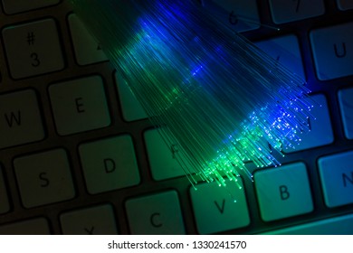 Colourful optic fibers illuminated on keyboard. High speed internet concept. Data transfer optic fiber cable. Bunch of many optical fibers, glowing different colors. Technology background.