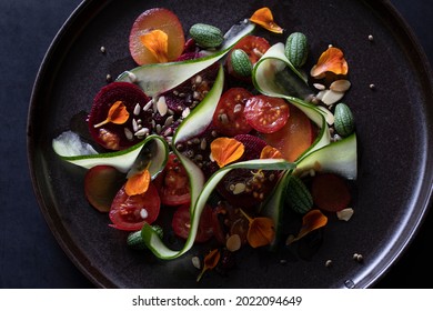 COLOURFUL ORGANIC SUMMER SALAD EDIBLE FLOWER GARNISH ON DARK PLATE  - Powered by Shutterstock