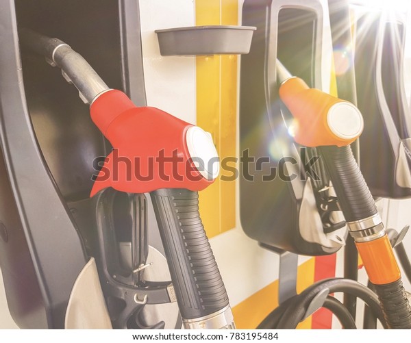 Colourful petrol pump fuel\
nozzles at Gas station service . Warm tone with lens\
flare,Selective focus