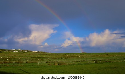 Colourful Rainbow Arc In Irish Landscape Landing On A  Rocky Outcrop In Middle Of Field