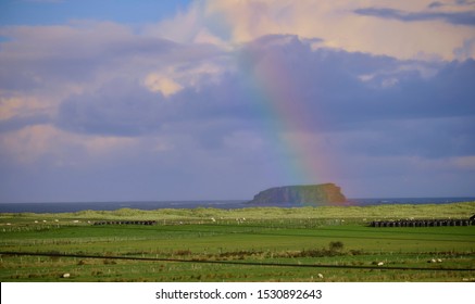 Colourful Rainbow In Irish Landscape Landing On A Large Rocky Island Of The Coast