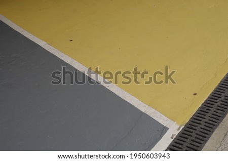 Colourful sections of a parking lot surface in grey and yellow surface with thick white outlines good for background with space for runaround or wraparound text
