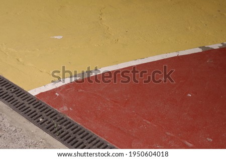 Colourful sections of a parking lot surface in red and yellow with thick white outlines good for background with space for runaround or wraparound text