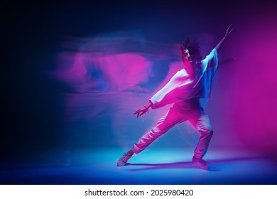 Colourful shot of dancing girl. Female dancer performer show expressive hip hop dance. Colored neon light, long exposure