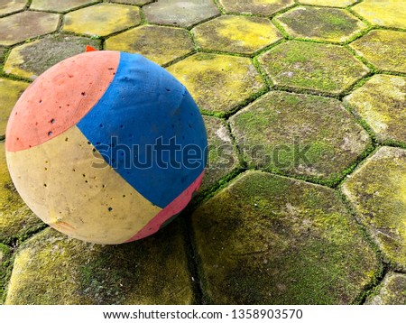 Colourful soccer ball on the mossy paving.