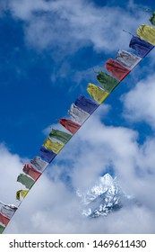 Colourful Tibetan Prayer Flag With Snow Mountain And Cloudy Blue Sky View On The Background, During The Way To Everest Base Camp On A Windy Day, Unesco Sagarmatha National Park, Nepal