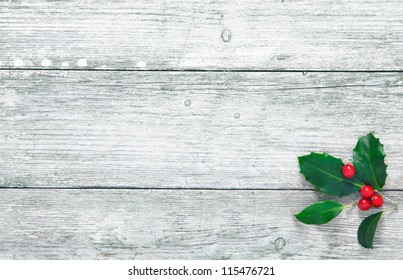 Colourful traditional Christmas holly with with red berries on grunge wood texture of old weathered boards with copyspace - Powered by Shutterstock