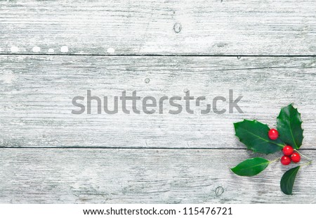 Colourful traditional Christmas holly with with red berries on grunge wood texture of old weathered boards with copyspace