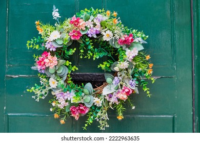 Colourful Wreath Of Artificial Flowers On A Vintage Green Front Door