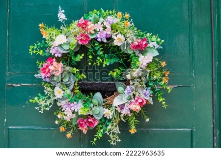 Colourful wreath of artificial flowers on a vintage green front door