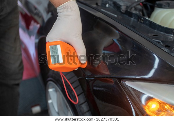 colourist man selecting color of car with paint\
matching scanner