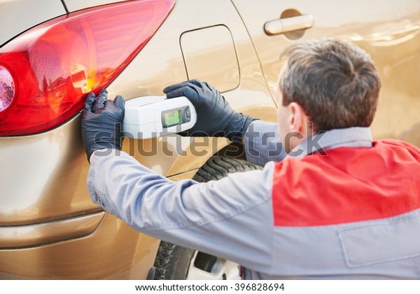 colourist man selecting color of car with paint matching\
scanner 